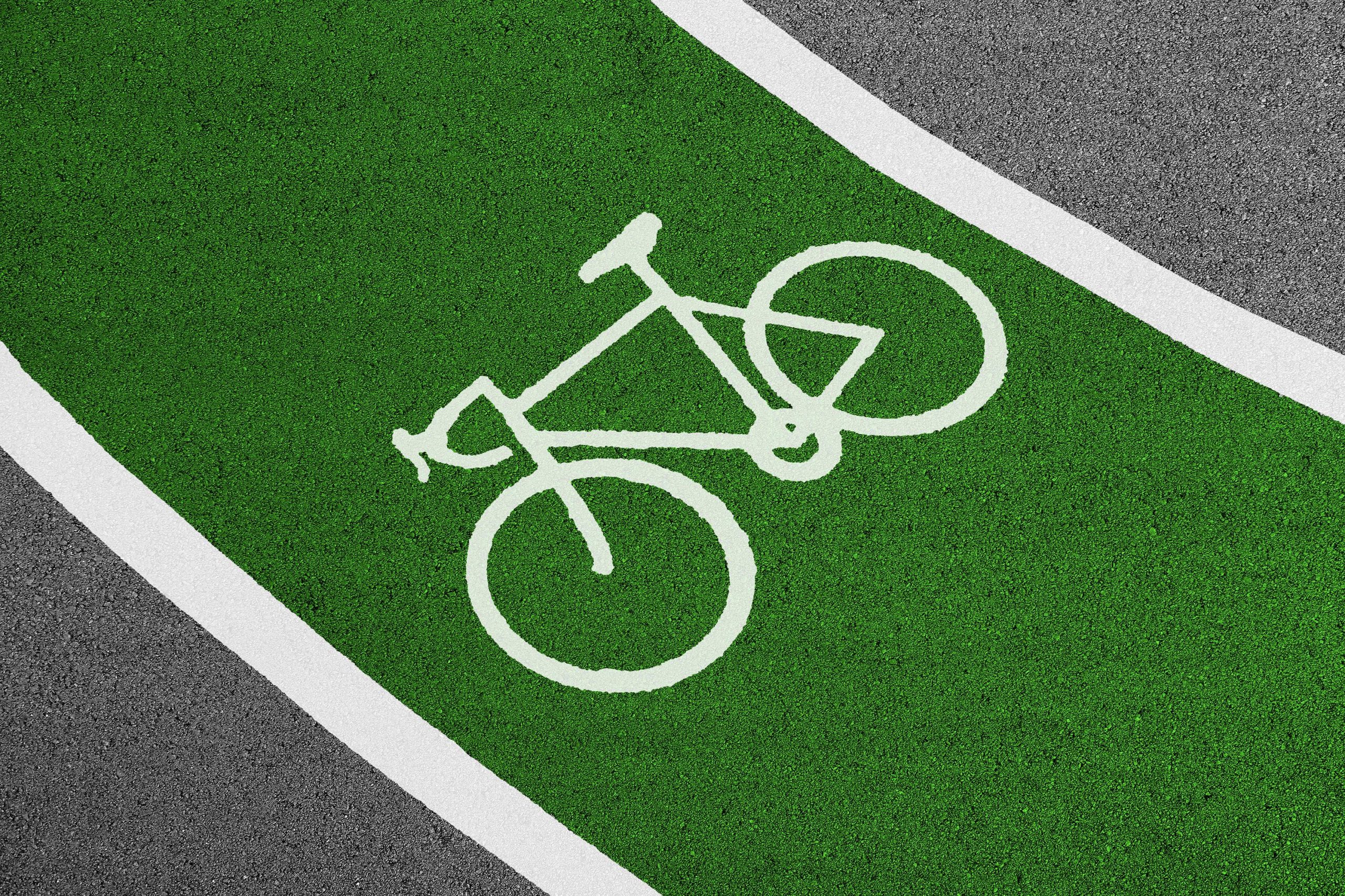 Despre noi Bright green bicycle lane with white bike symbol and clear road texture.